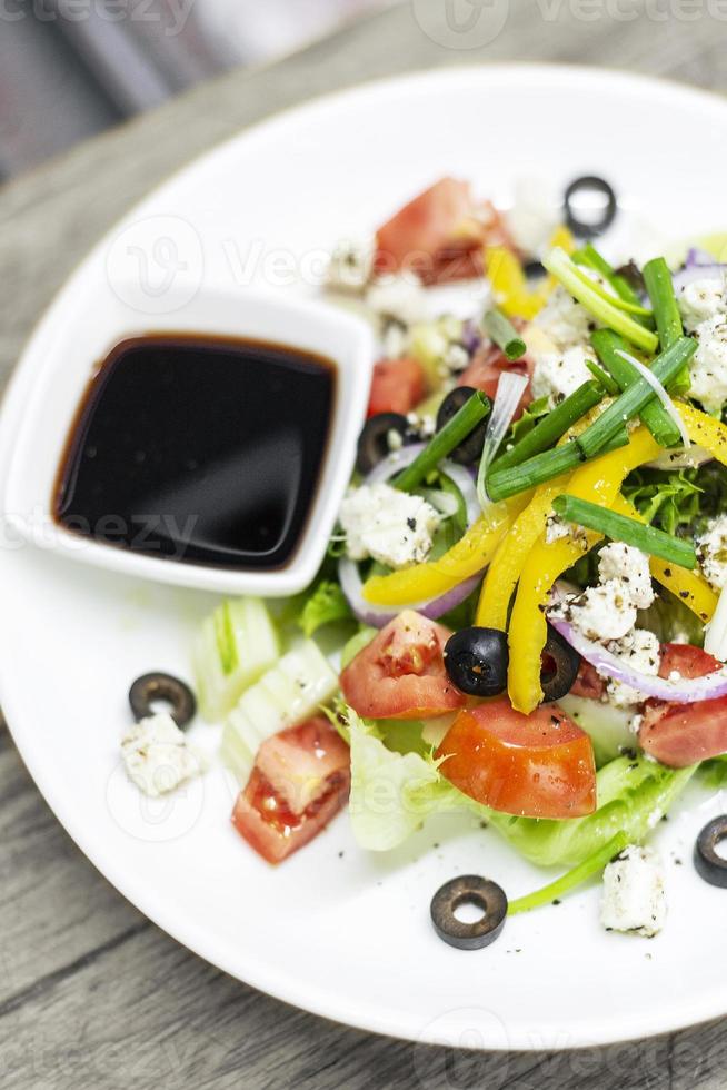 Traditional Greek salad with feta cheese and mixed organic vegetables on wooden table photo