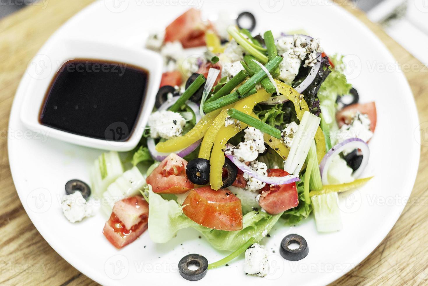 Traditional Greek salad with feta cheese and mixed organic vegetables on wooden table photo