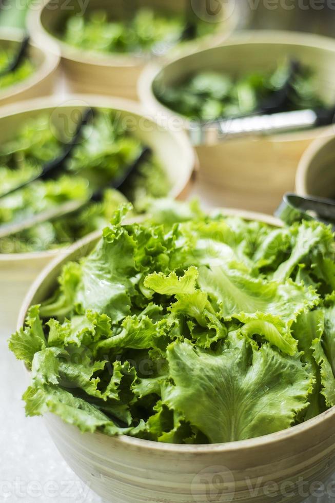 Bowls of fresh organic green lettuce leaves in salad bar display photo