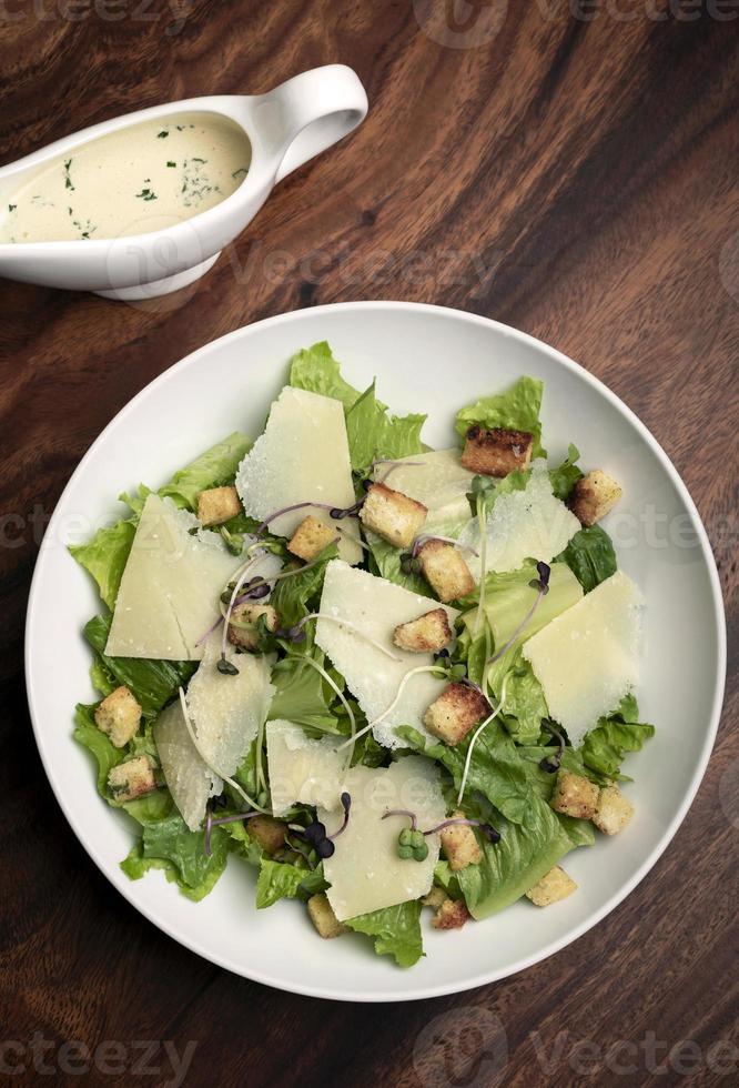 Ensalada César con queso parmesano y picatostes sobre mesa de madera foto