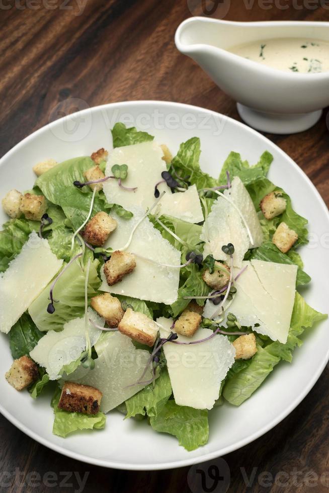 Caesar salad with parmesan cheese and croutons on wood table photo