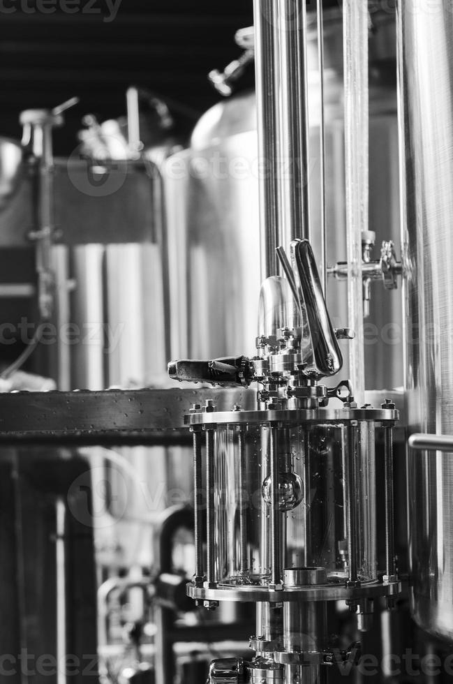 Industrial beer brewing equipment detail in brewery interior in black and white photo