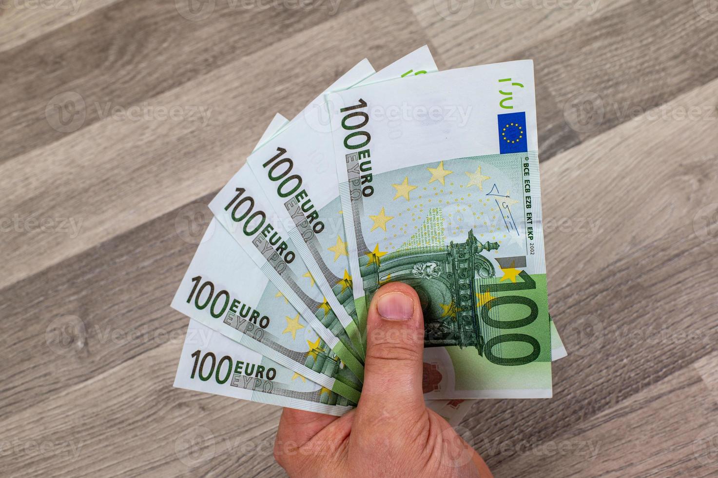 man's hand holding fanned 100 euro banknotes photo