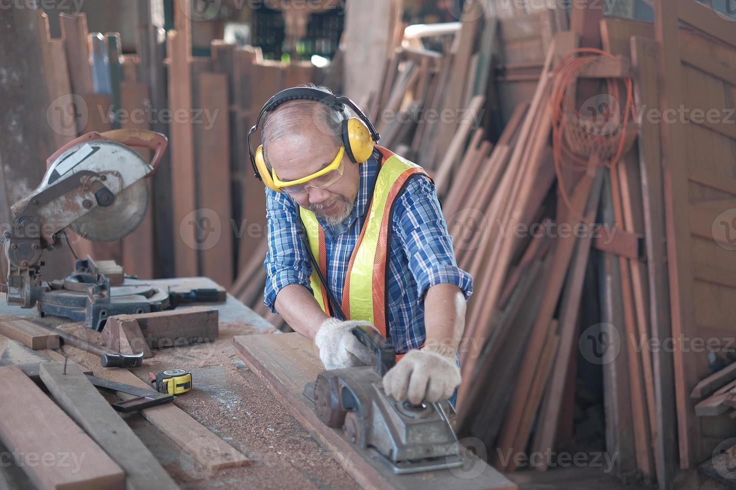 Senior Asian male carpenter is working in lumber factory. photo