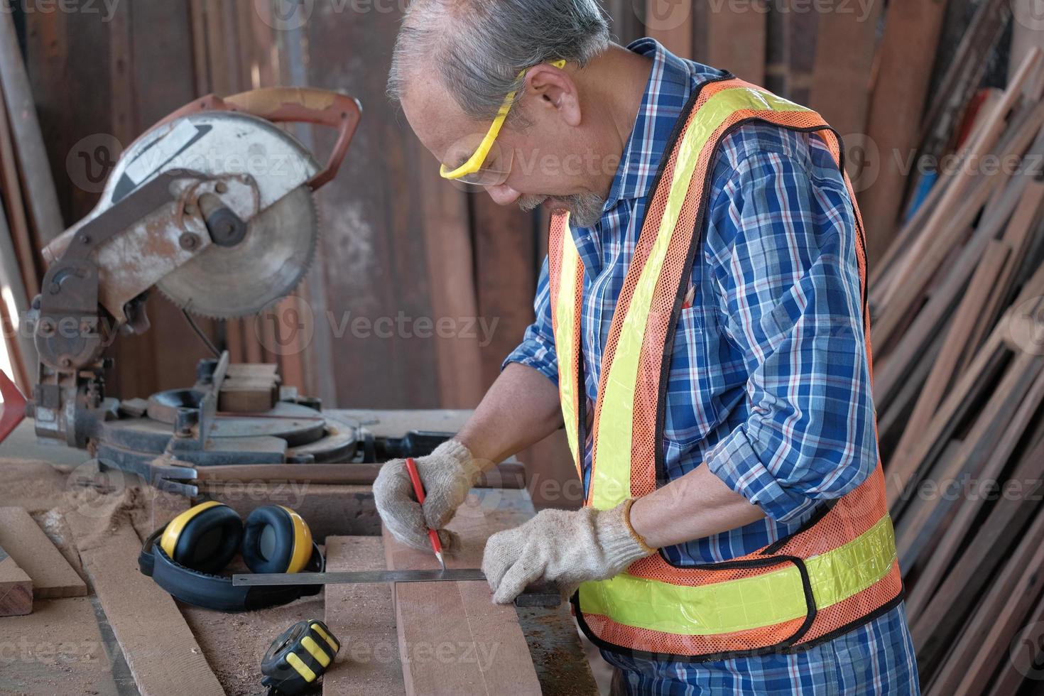 Asian senior carpenter man in wooden factory. photo