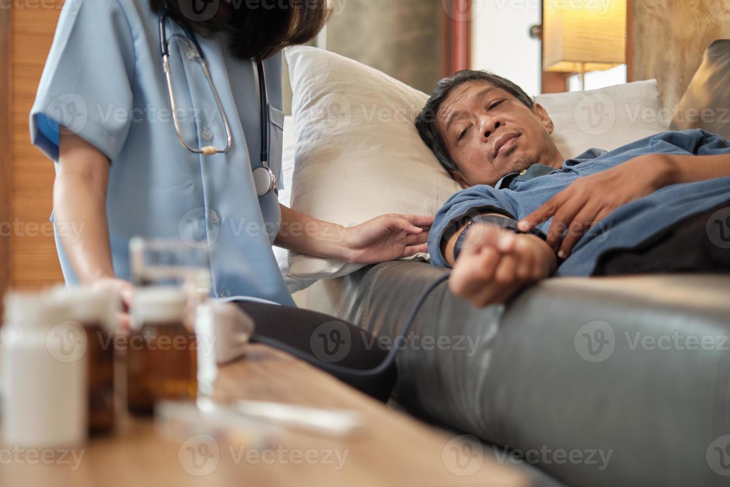 Doctora comprobando la salud del paciente masculino anciano asiático en casa. foto