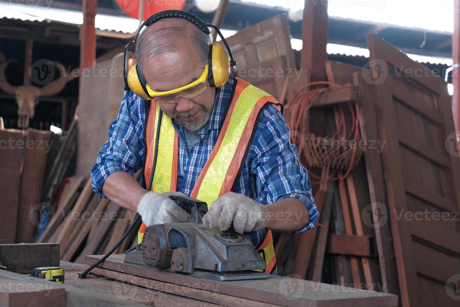 Hombre asiático carpintero maduro en fábrica de madera. foto