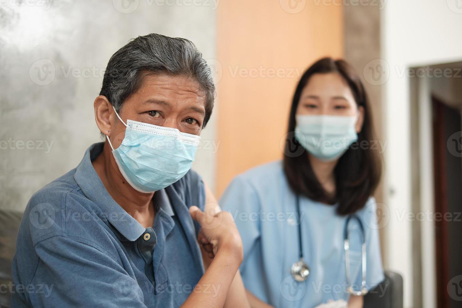 Elderly patient points finger at arm after vaccinating. photo