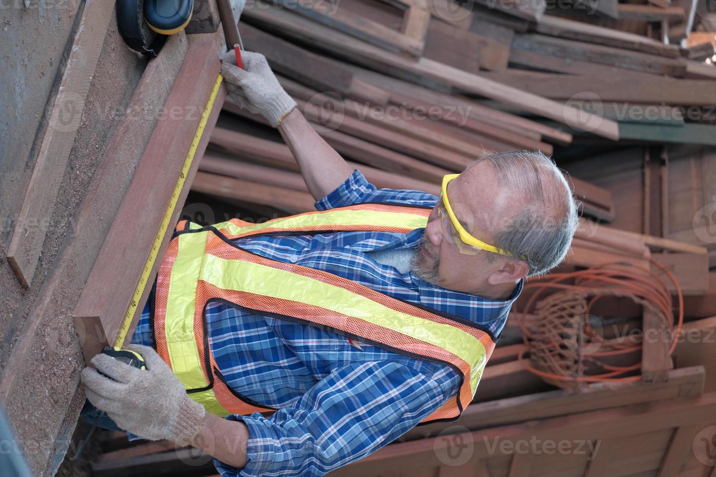 Senior Asian male carpenter working in a wooden factory. photo