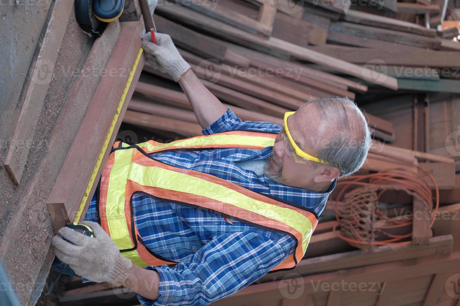 Carpintero masculino asiático senior que trabaja en una fábrica de madera. foto