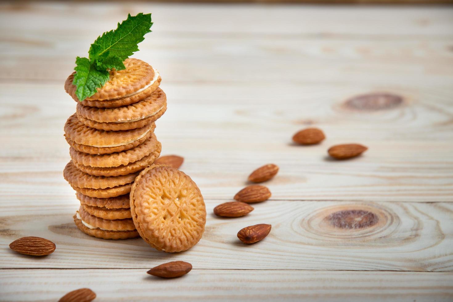 Galletas horneadas rellenas con crema de leche y almendras sobre mesa de madera foto