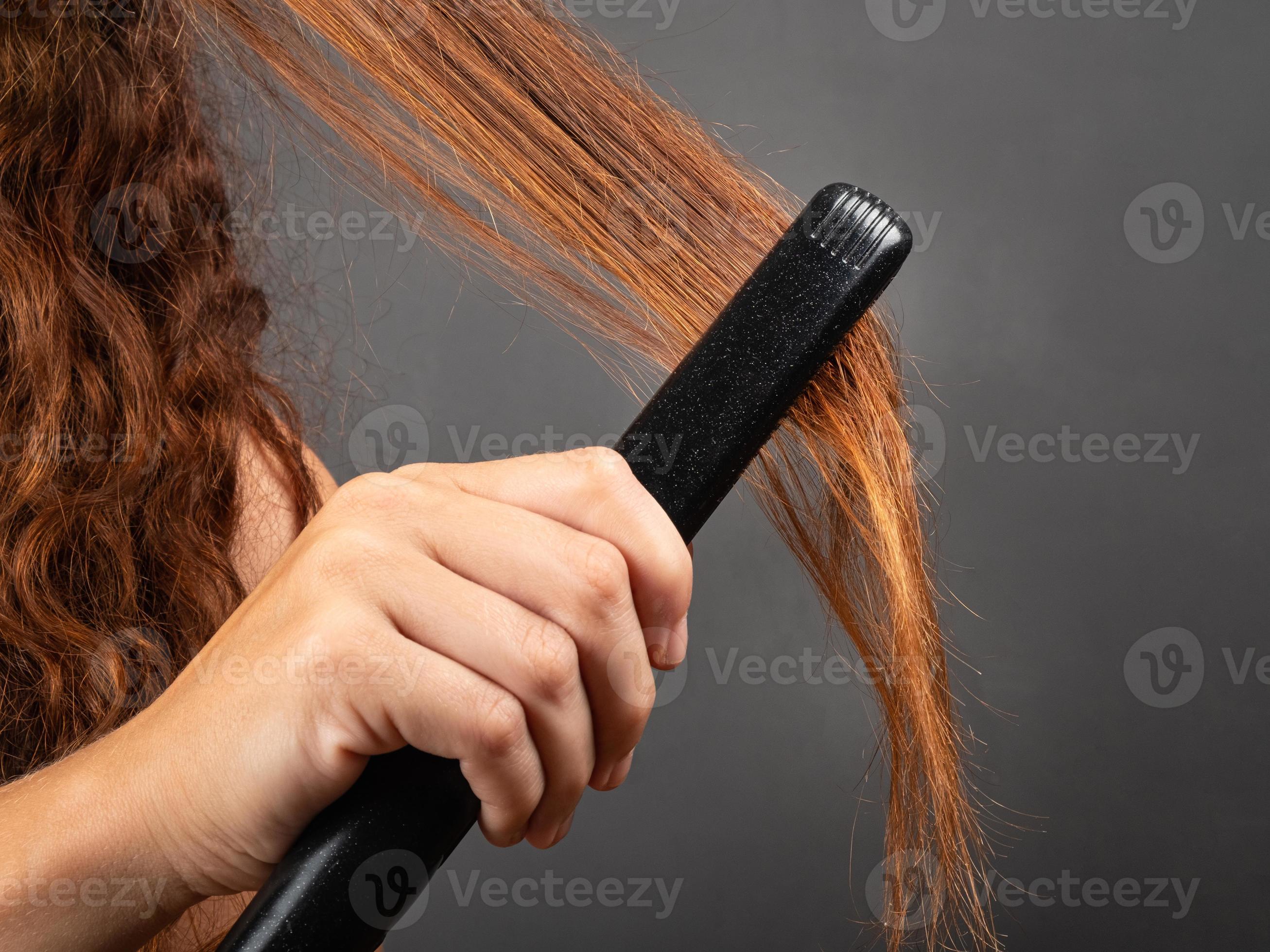 Girl smooths curly hair with a hair straightener, curling iron. 3246981  Stock Photo at Vecteezy