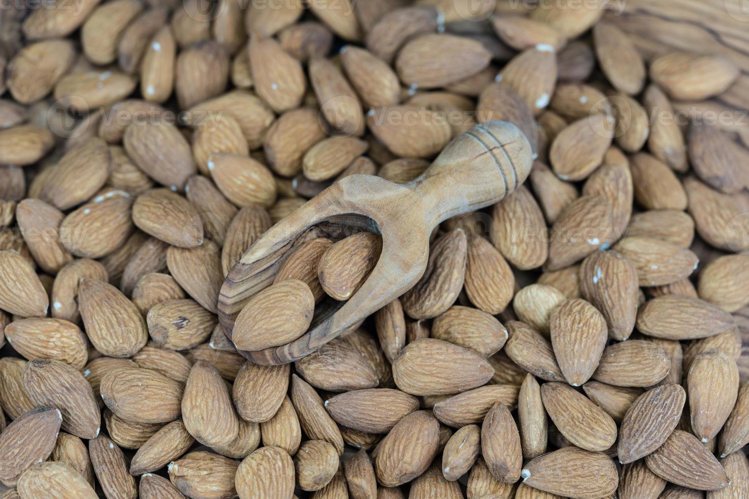 un montón de almendras peladas en madera de olivo foto