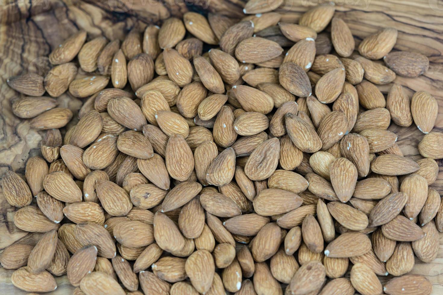 un montón de almendras peladas en madera de olivo foto