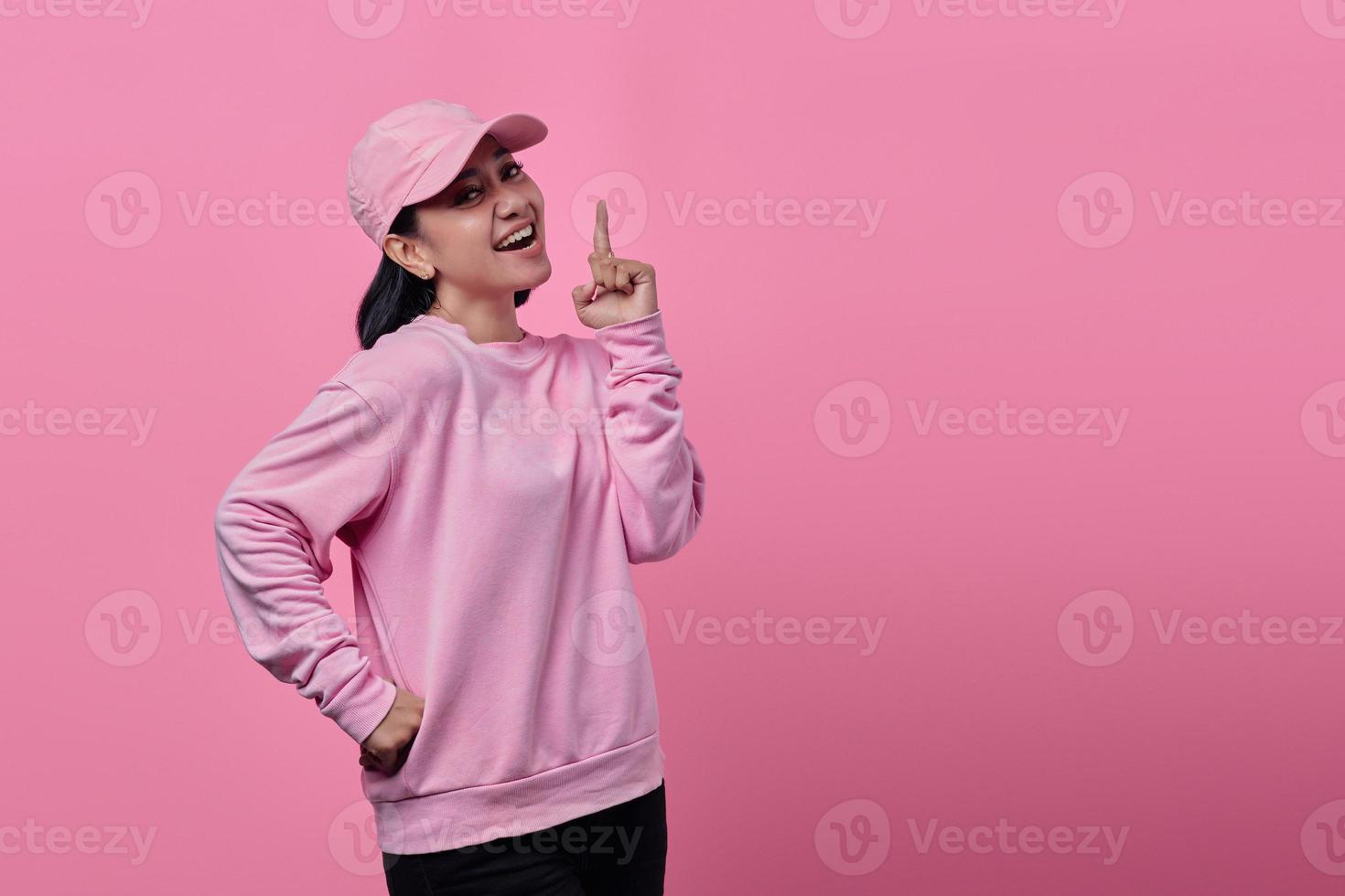 Woman smiling broadly looking with finger pointing at empty space photo