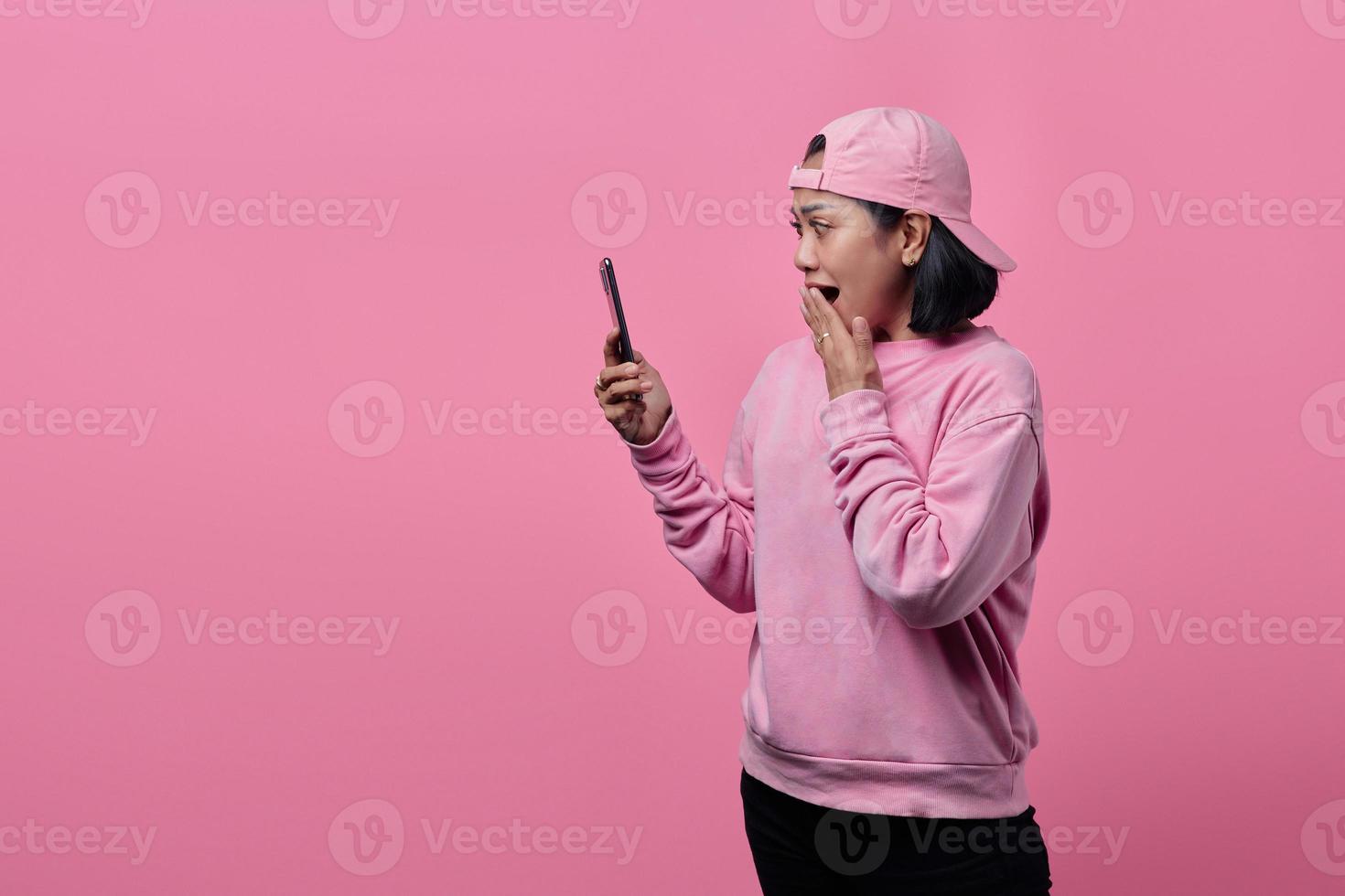 joven mujer asiática sorprendida mediante teléfono móvil foto