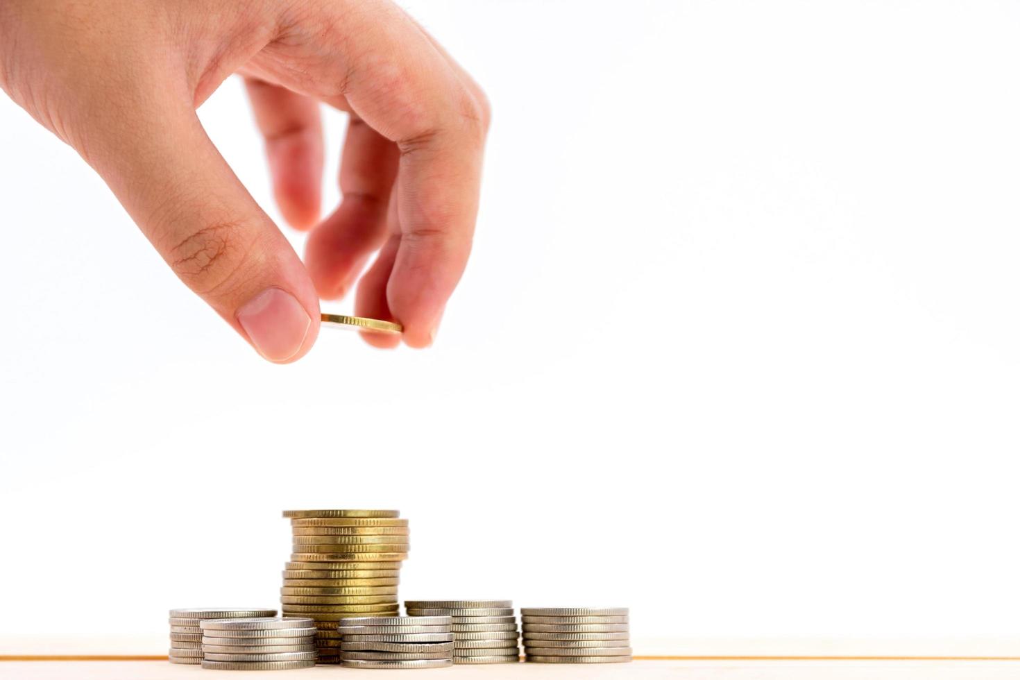 Closeup of human hand putting a coin on a pile of coins photo