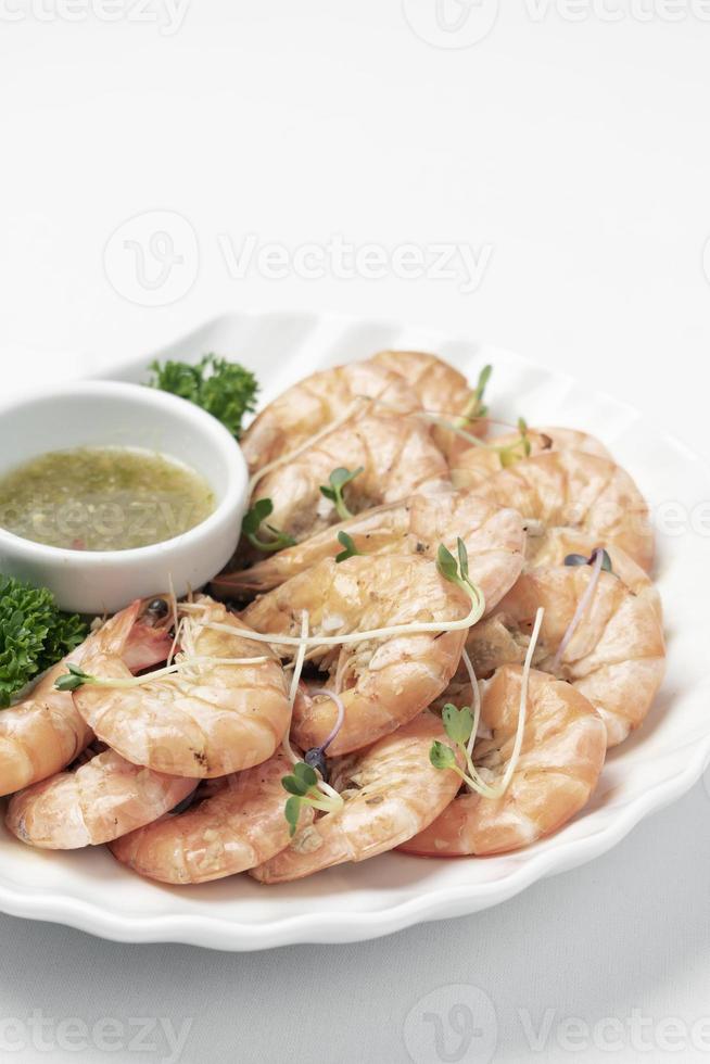 Fresh boiled prawns with zesty citrus dipping sauce on white background photo