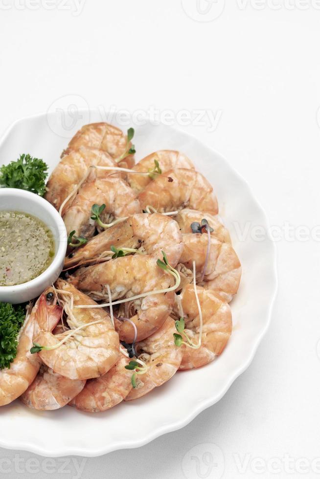 Fresh boiled prawns with zesty citrus dipping sauce on white background photo