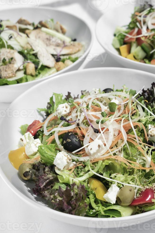 Ensaladas orgánicas frescas mixtas en tazones sobre la mesa de restaurante blanco foto