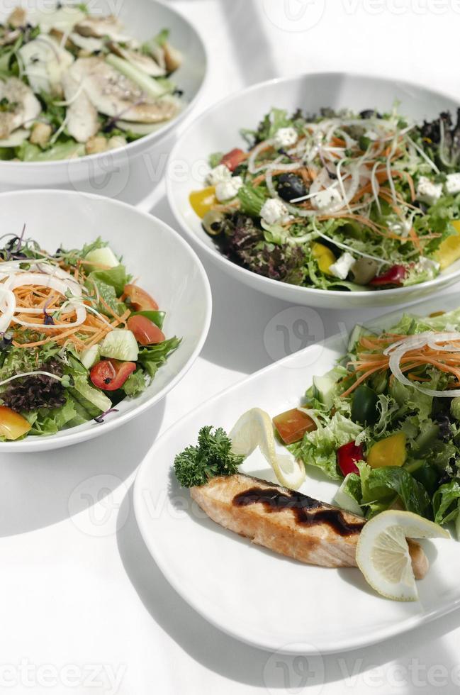 Mixed fresh organic salads in bowls on white restaurant table photo