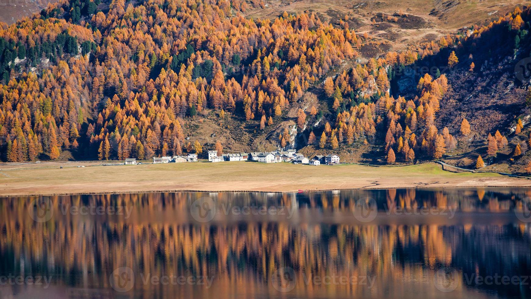 A mirror of autumn plants of a mountain lake village photo