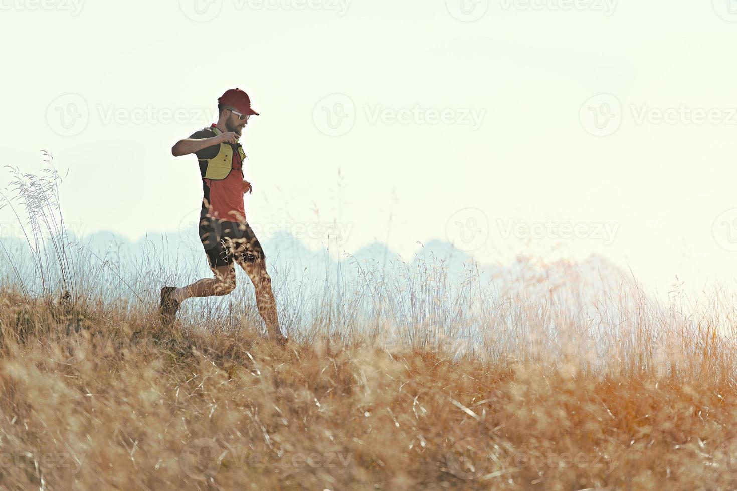 El hombre corre cuesta abajo entre los prados de las montañas otoñales. foto