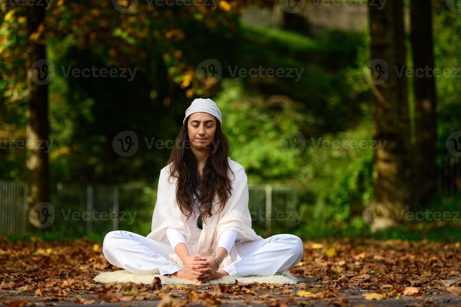 Mujer de blanco en el parque de otoño mientras hace yoga foto