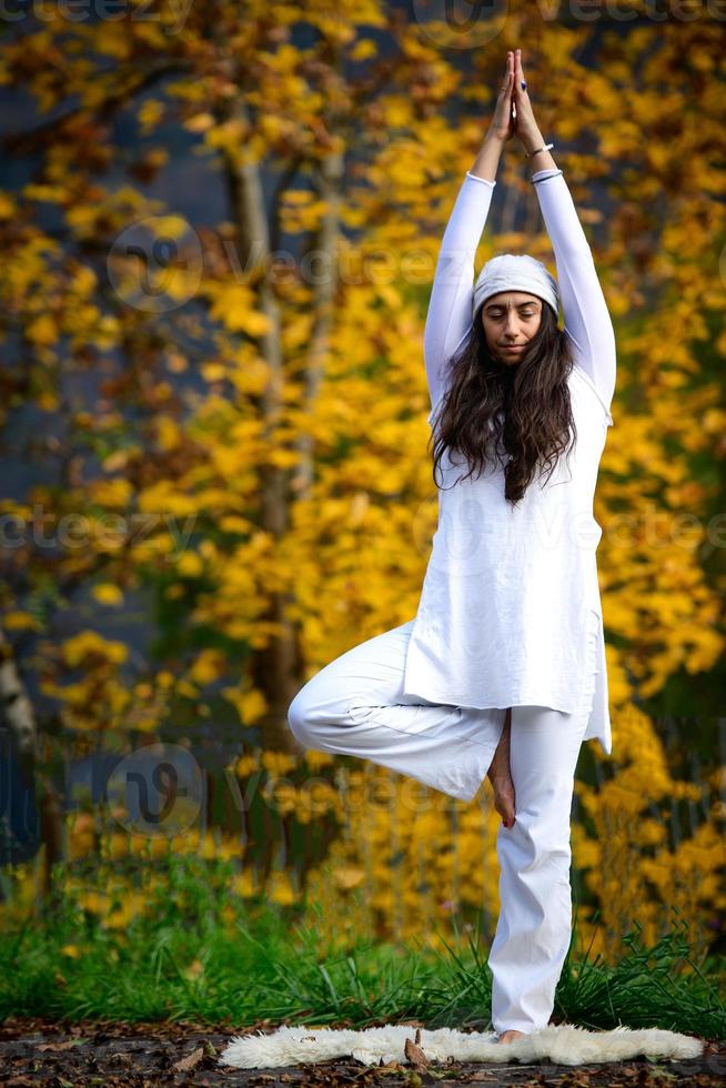 Mujer joven durante una práctica de yoga en la naturaleza de otoño foto