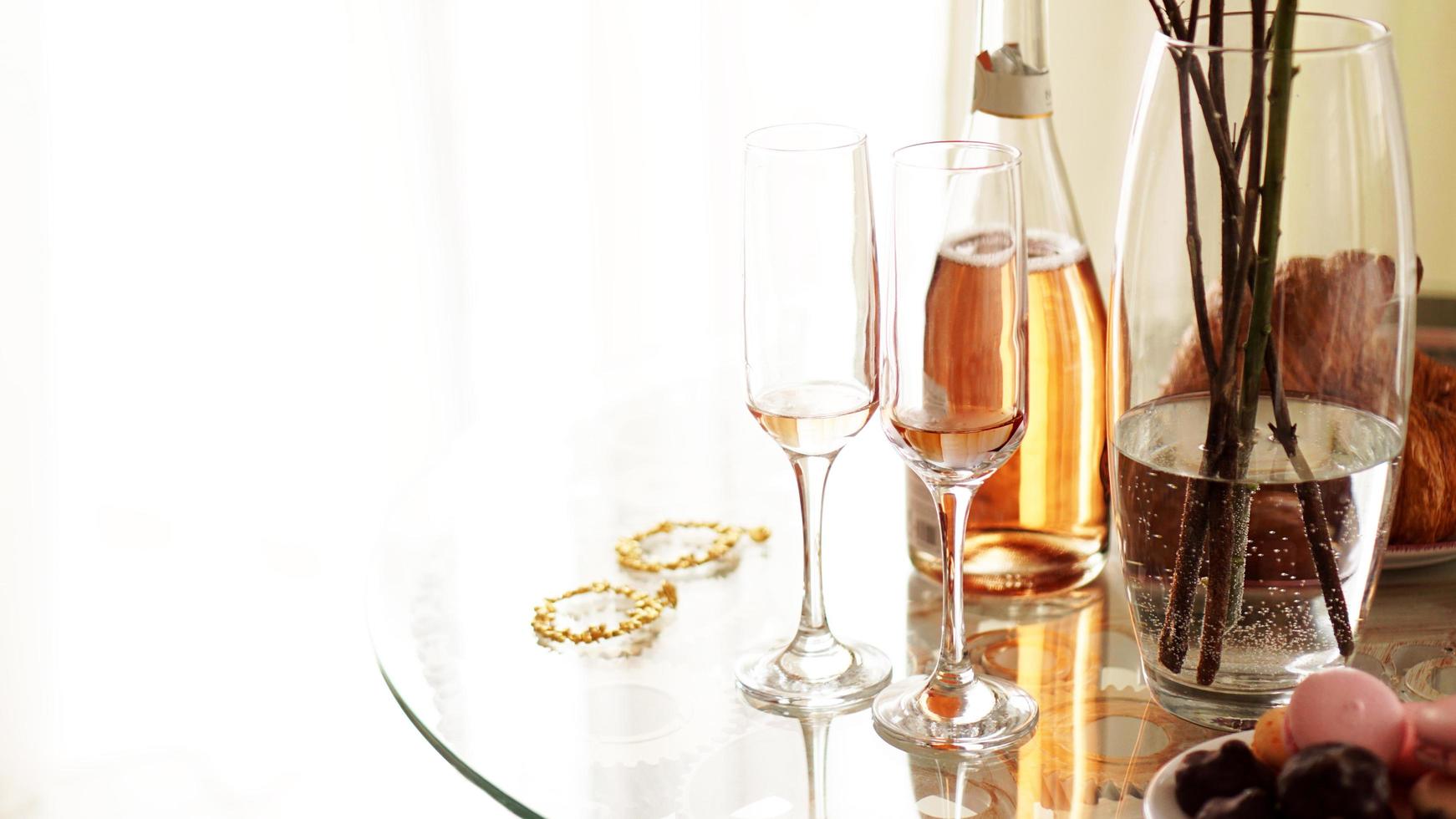 Glass table on a light background. Two glasses and a bottle photo