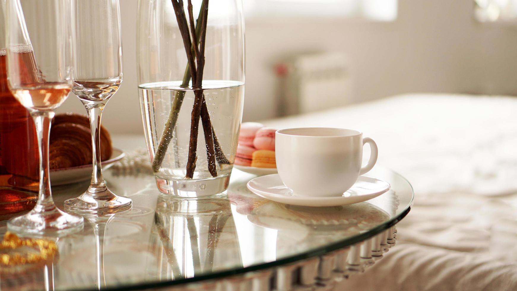 mesa de cristal con una taza de café, macarrones dulces. foto