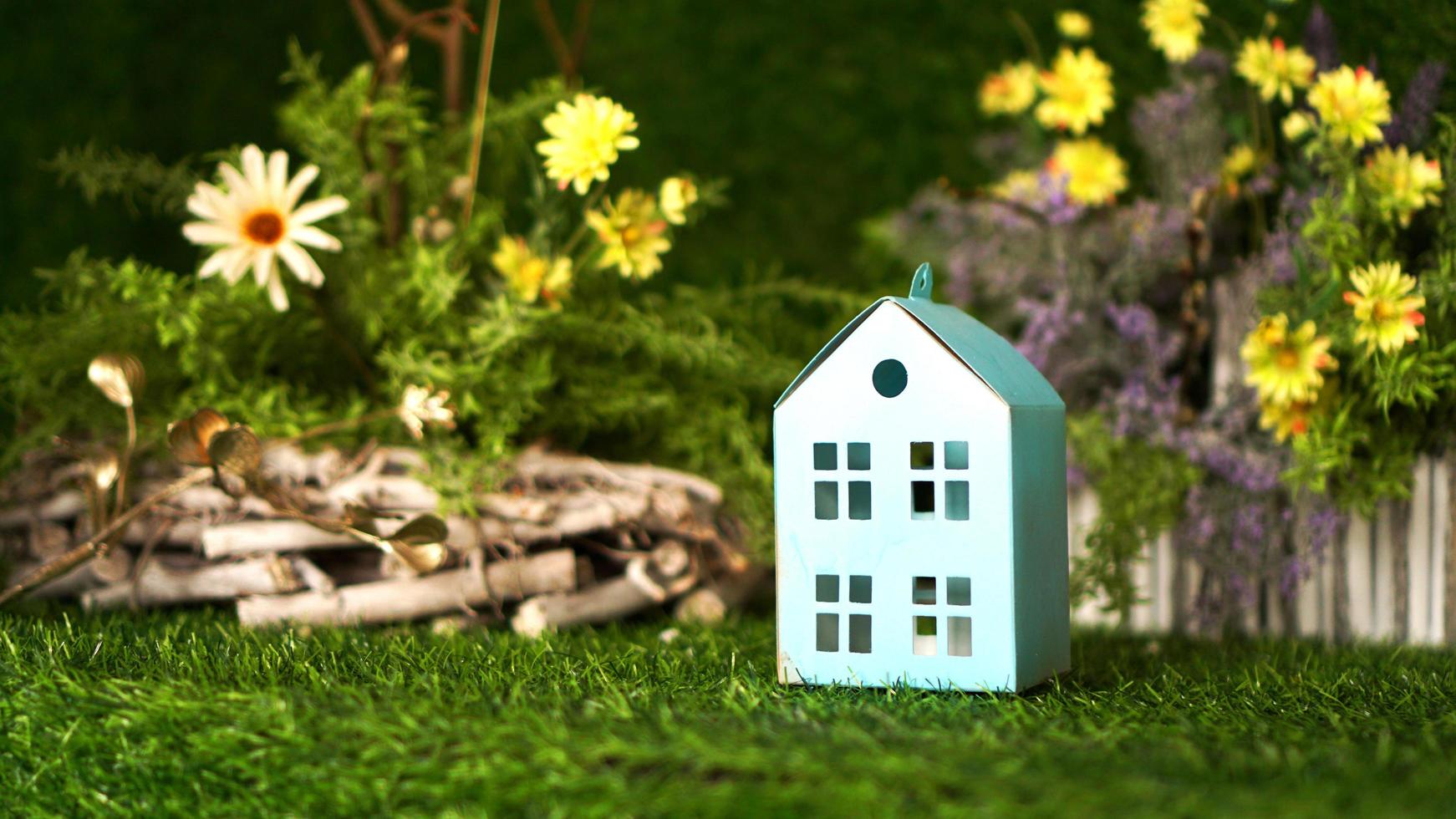 Cardboard blue house on background of green spring photo