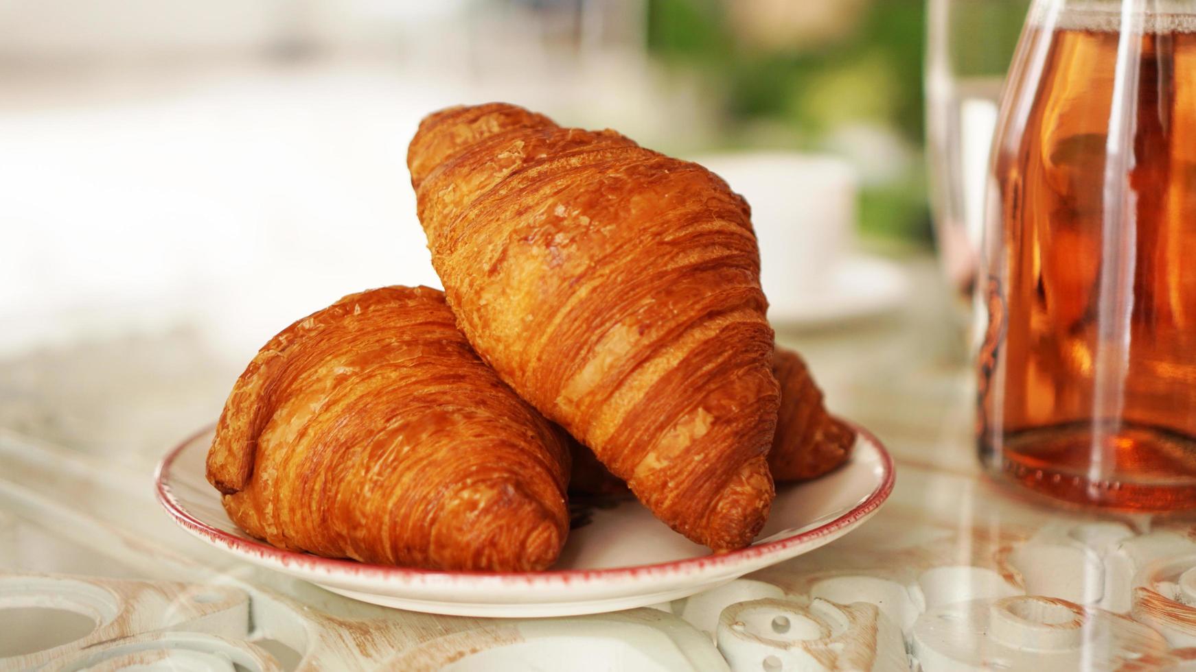 Two fresh croissants on a plate on a glass table. Breakfast concept photo