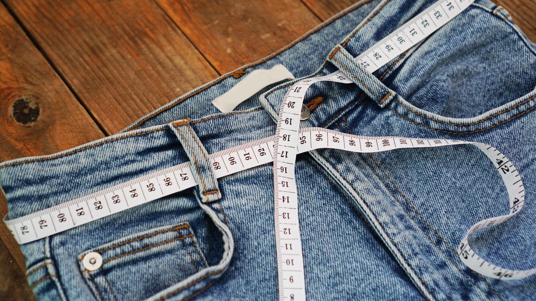 Measuring tape and jeans on a wooden background photo