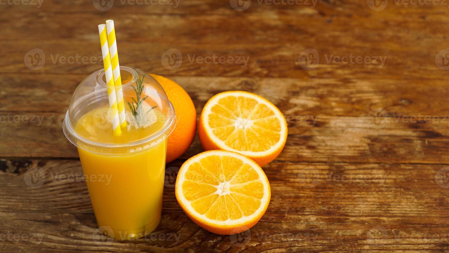 Jugo de naranja en comida rápida taza cerrada con tubos sobre mesa de madera foto