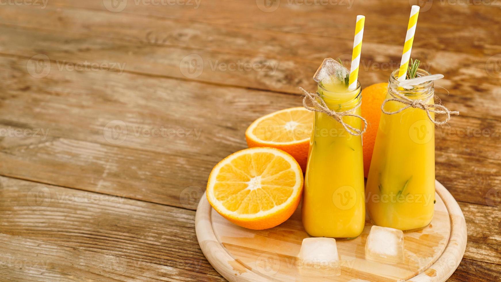 Orange juice on a wooden tray. Sliced orange and ice cubes photo