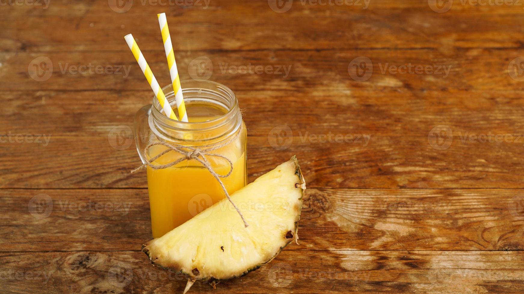 Pineapple juice on a wooden background. A glass jar with juice photo