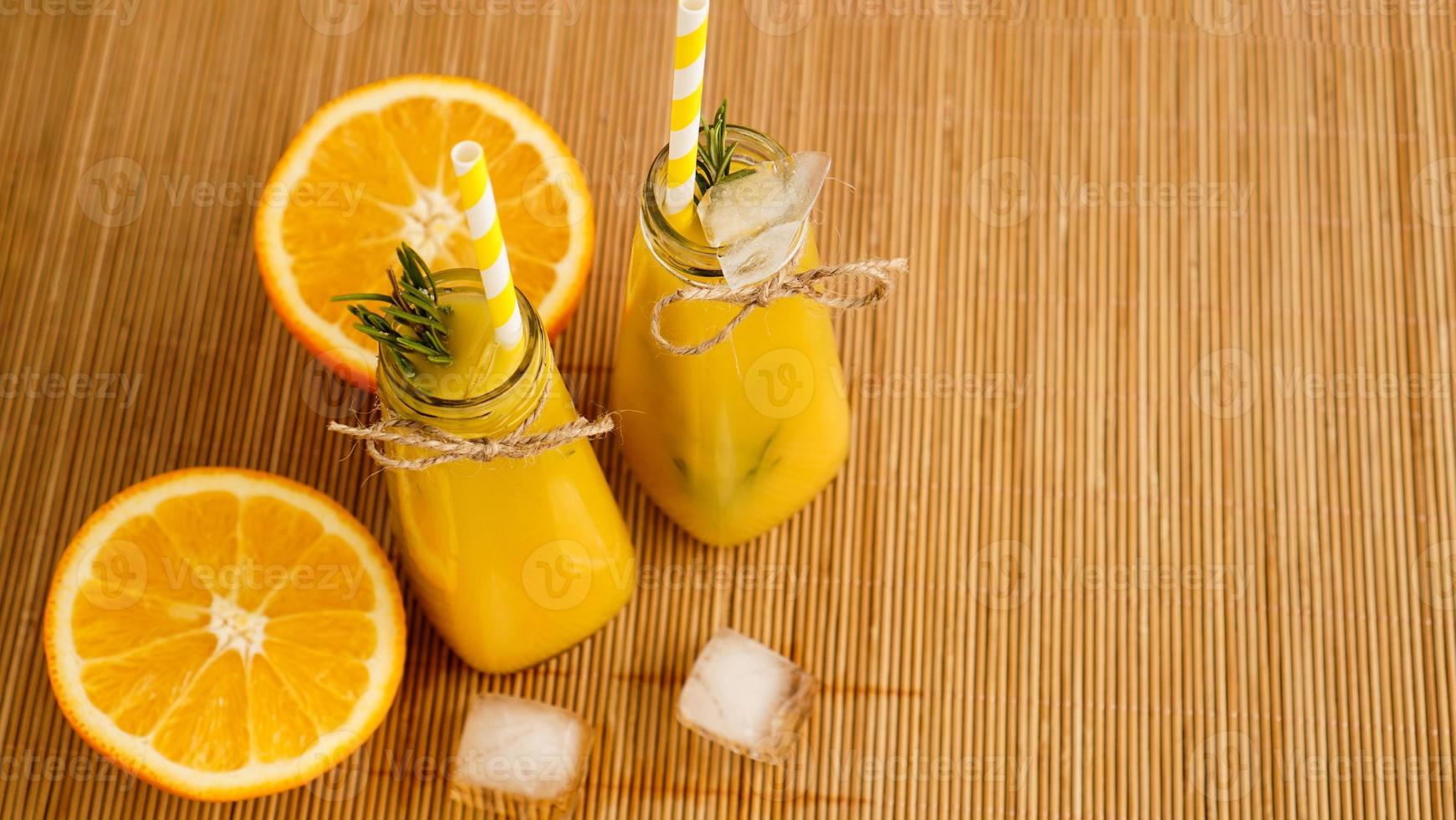 Orange juice bottles and paper straws. Icy drink on a sunny day photo