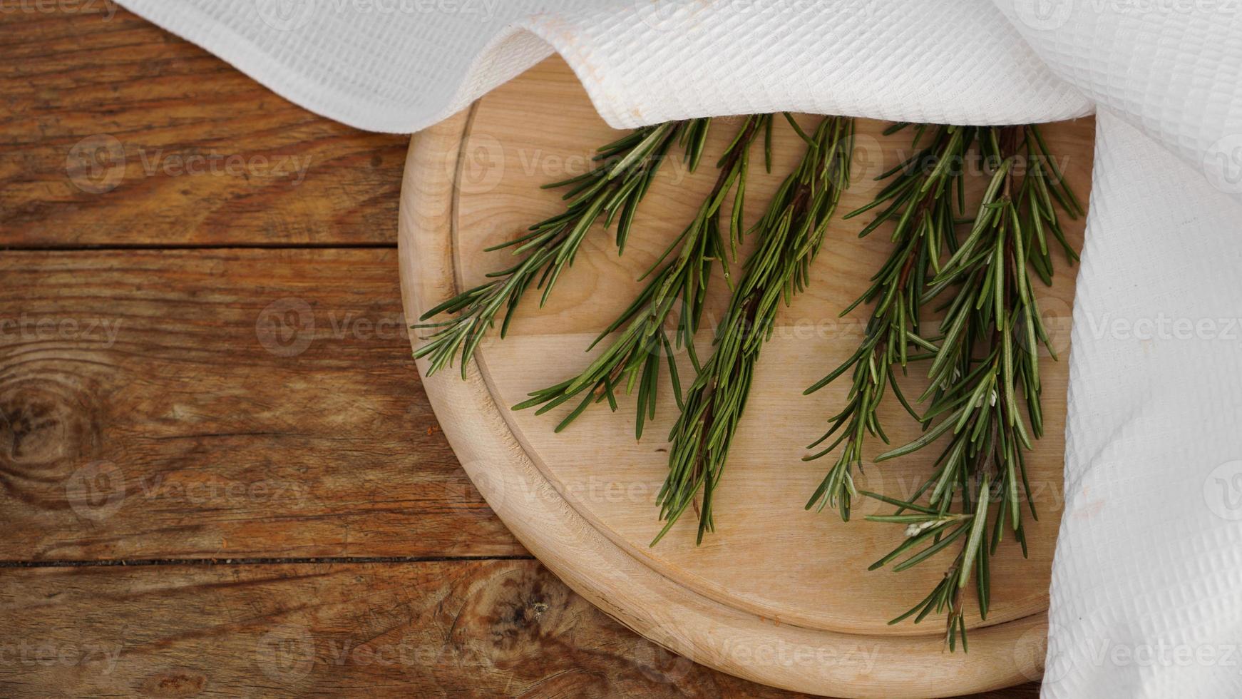 Sprigs of rosemary on a wooden board for cutting. Rustic style photo