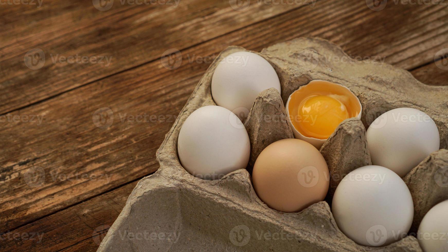 White eggs carton and cracked egg half with yolk top view photo