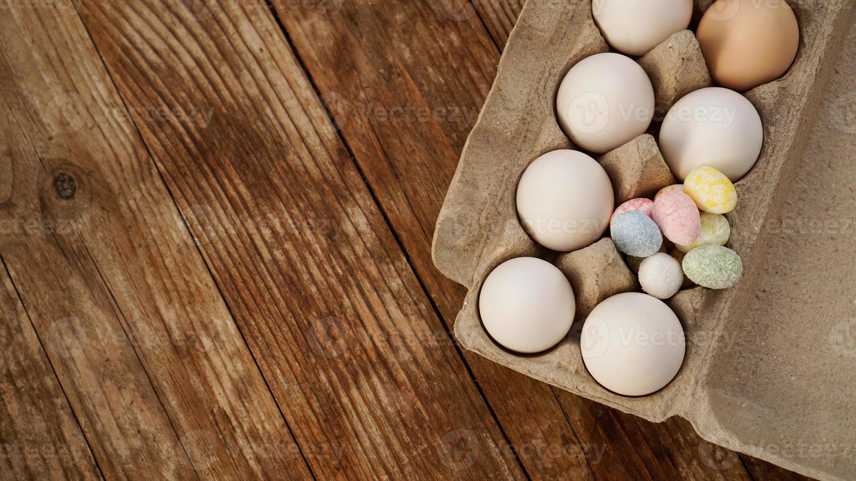 Chicken eggs in a cardboard tray and Easter decor on a wooden photo