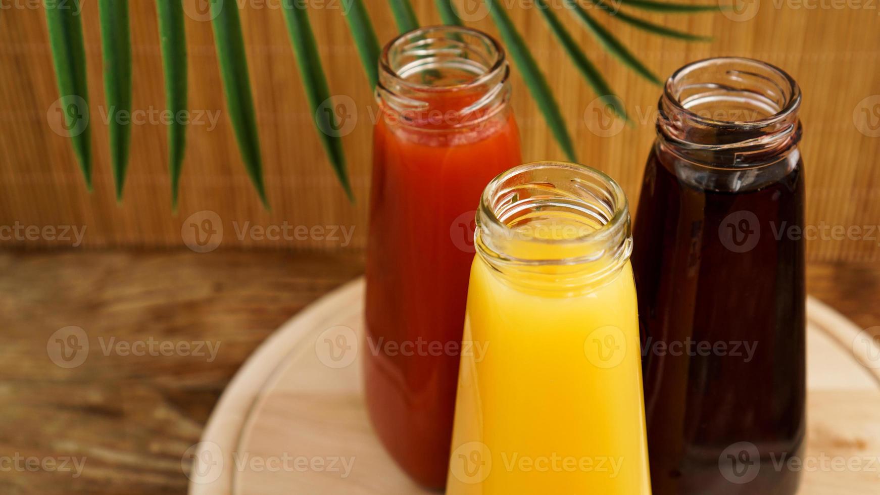 Botellas de vidrio de jugo fresco y saludable sobre fondo de madera foto