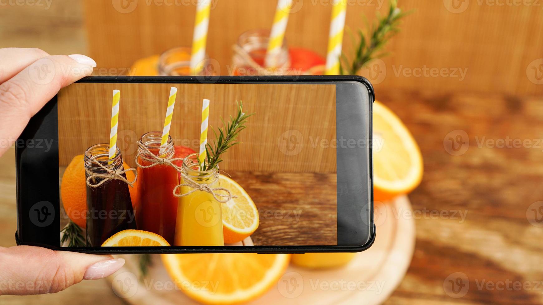 Mujer tomando foto de jugo de frutas en su teléfono inteligente