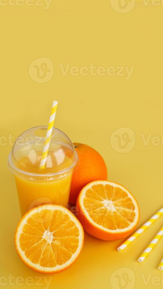 Orange juice in fast food closed cup with tube on yellow background photo