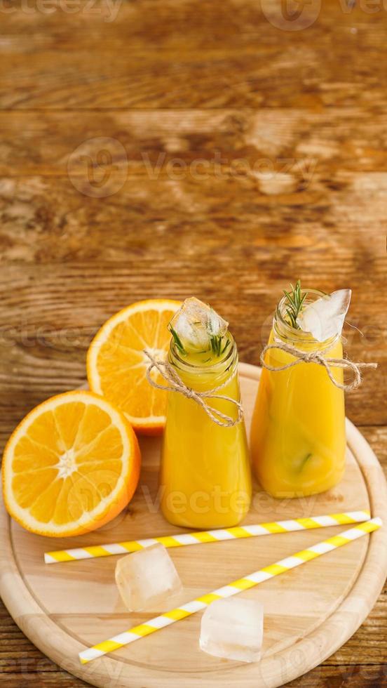 jugo de naranja en una bandeja de madera. rodajas de naranja y cubitos de hielo foto