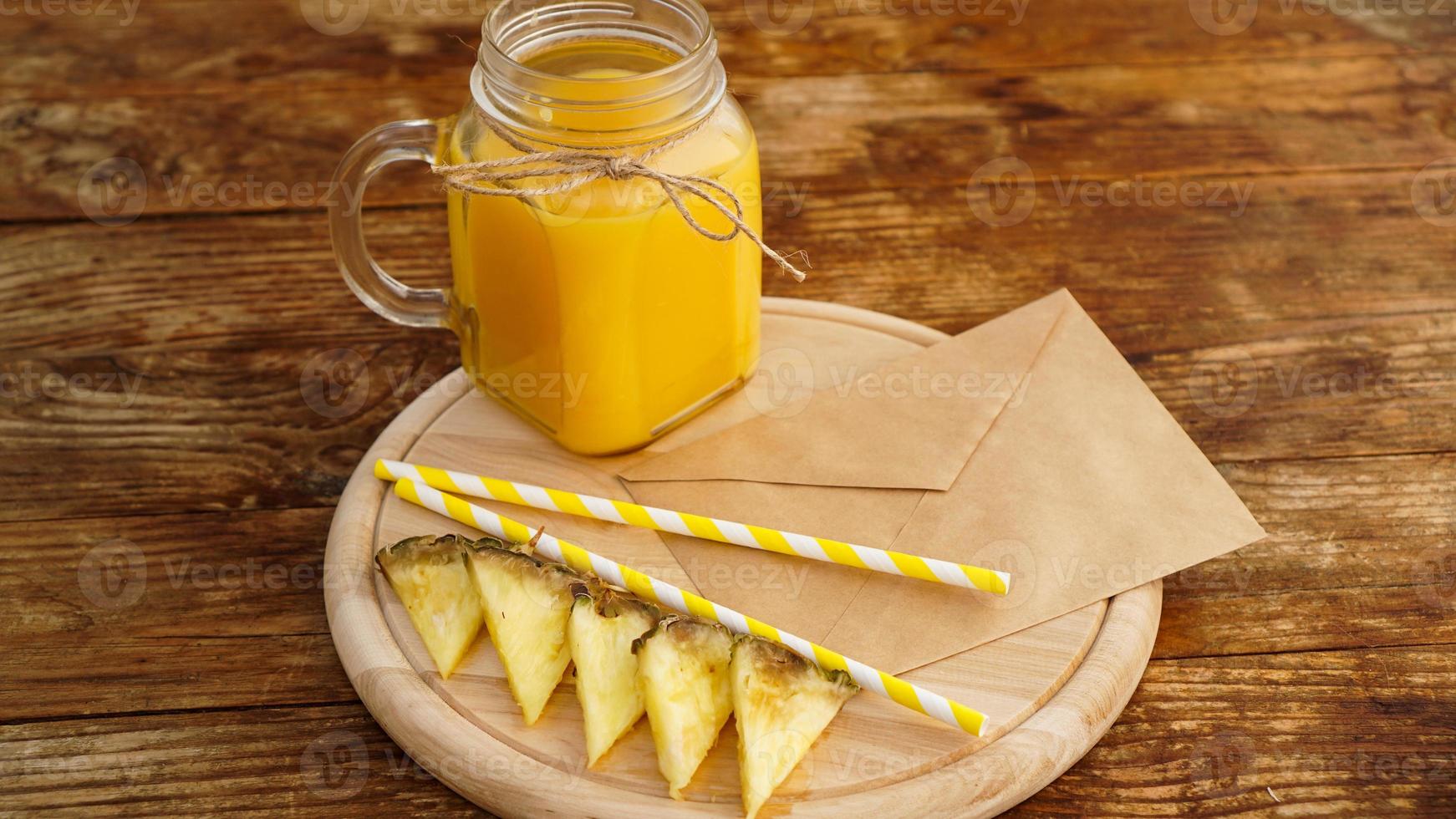 Pineapple juice in a glass jar on a wooden background photo