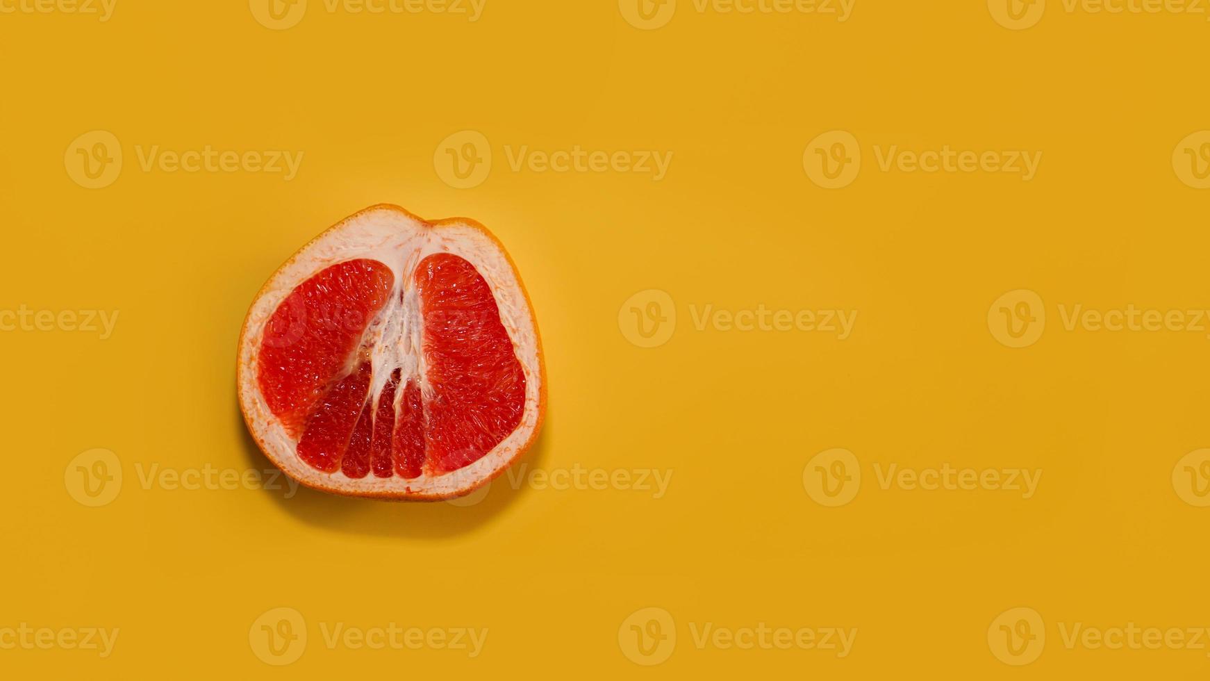 Sliced red grapefruit with copy space on bright yellow photo