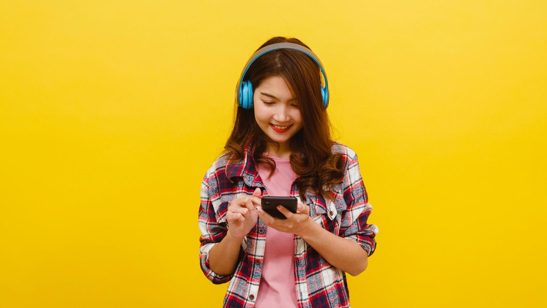 Asian lady wearing headphones listening to music from smartphone. photo