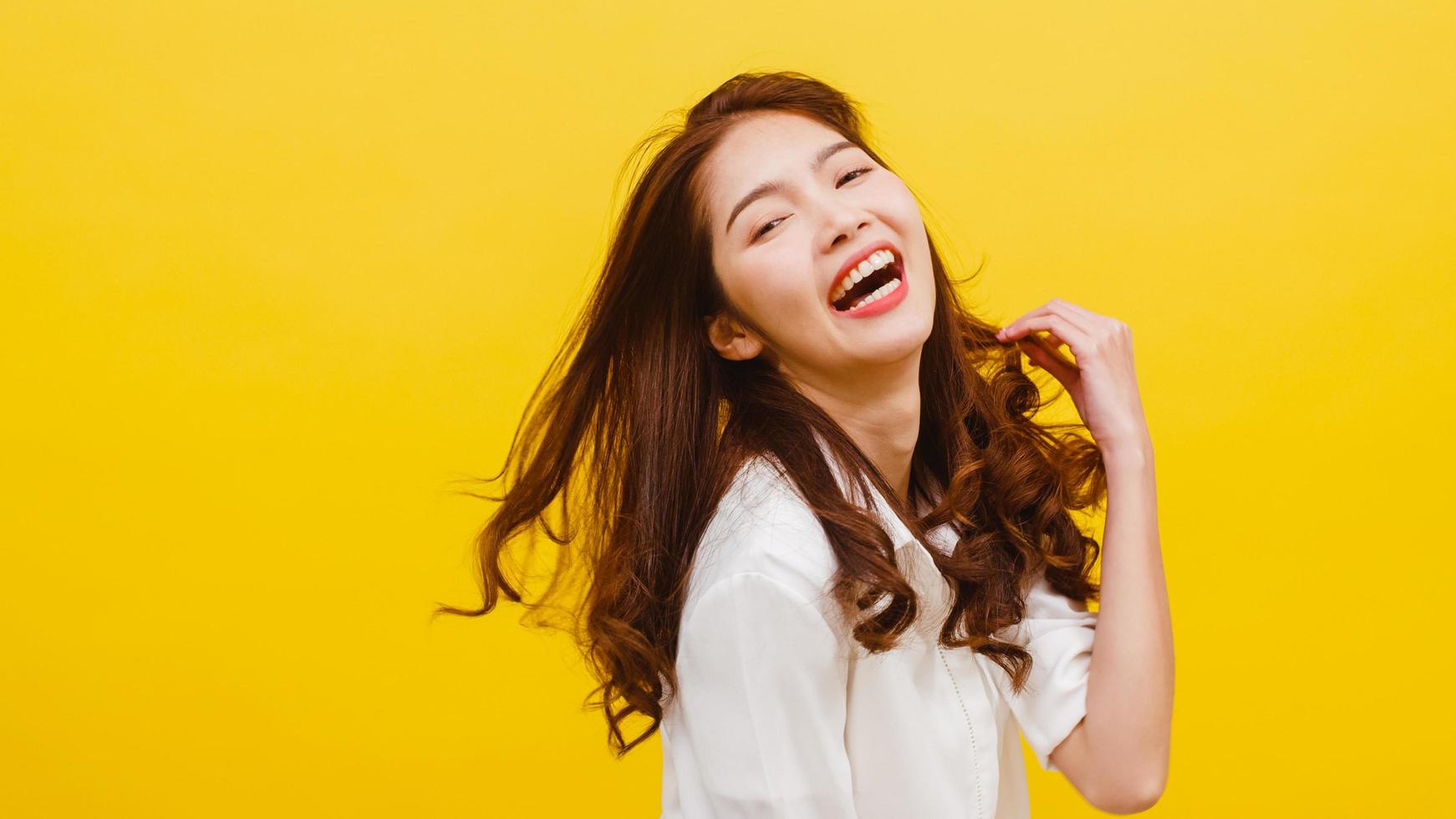 Young Asian lady listening to music and dancing on yellow background. photo