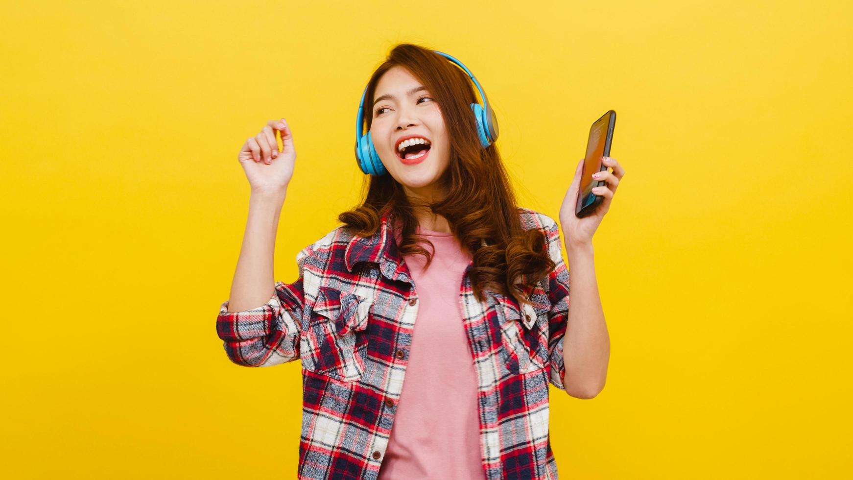 Young Asian lady wearing headphones listen to music from smartphone. photo